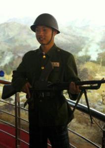在抗美援朝纪念馆内，游客可装扮成上个世纪朝鲜半岛战争时的军服、扛着假枪，站在一副战争全景图跟前拍照留念。