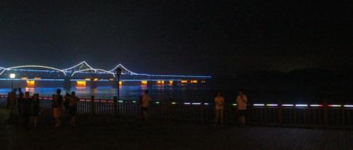 夜晚的鸭绿江畔，中朝友谊桥亮着彩灯，从繁华的丹东延伸至漆黑一片的朝鲜新义州。